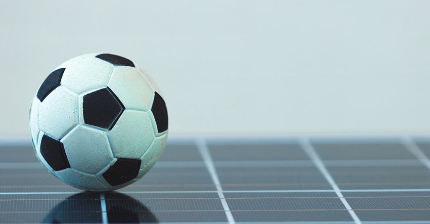 Bola de futebol preta e branca em cima de um painel fotovoltaico